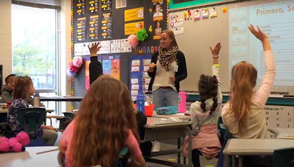 students raise hand in second grade classroom