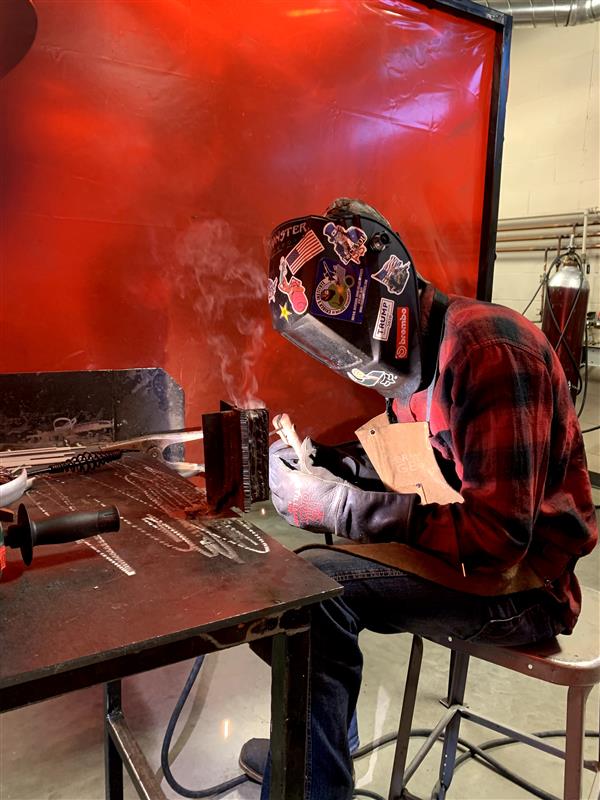 Students work on projects in the welding booth