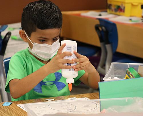 photo of boy putting glue on paper