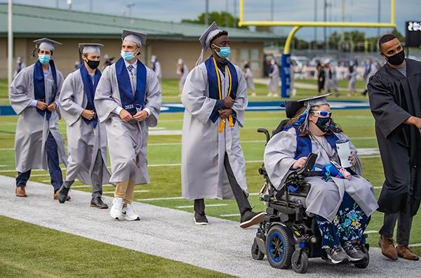 students walking to graduation on football field