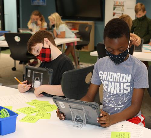 photo of elementary students working on tablets