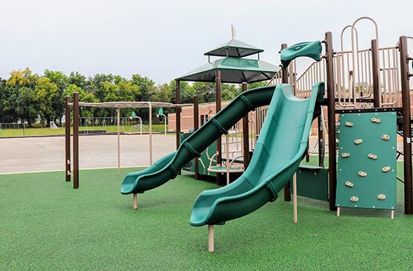 slides, climbing wall and other playground equipment on astroturf