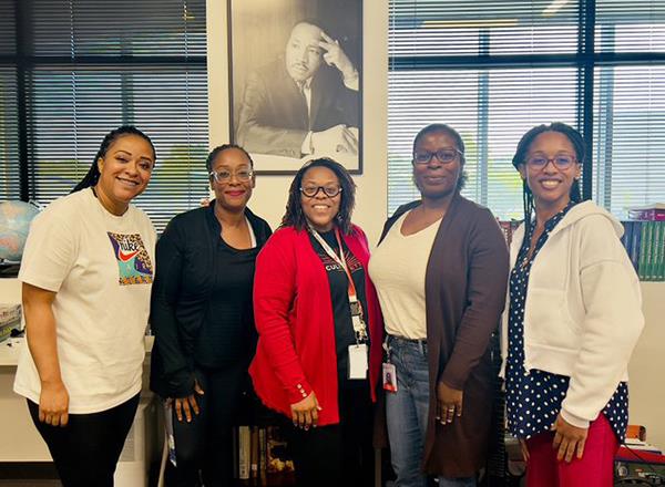 group members pose for a photo in front of an MLK poster