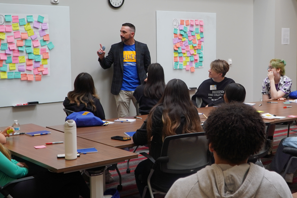 man gives speech to students from front of conference room